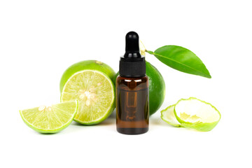 Lime essential oil in glass bottle and fresh lime fruits with green leaf isolated on white...
