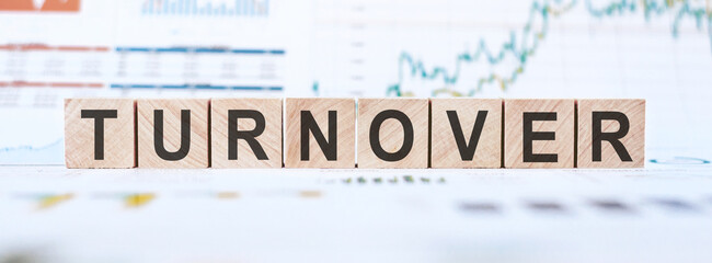 On a light background, graphs, diagrams and wooden cubes with the word TURNOVER.