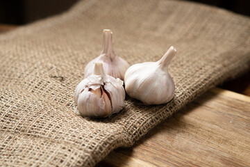 Three heads of dry garlic on a wooden background.