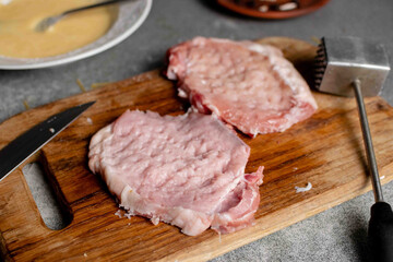 Two pieces of beaten meat on a cutting board. Cooking pork chops.
