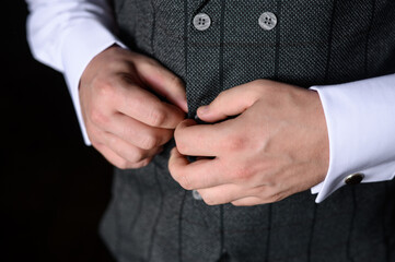 Obraz premium A man in a white shirt fastens a button on his jacket, close-up. Young modern businessman. Wedding day.