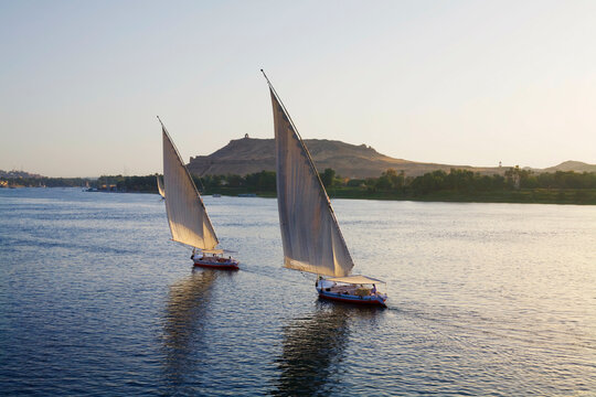 Egypt, Aswan, Two feluccas sail up Nile River at sunset