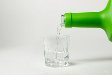 Vodka is poured into a glass on a white background. Strong alcoholic drink. Alcohol addiction