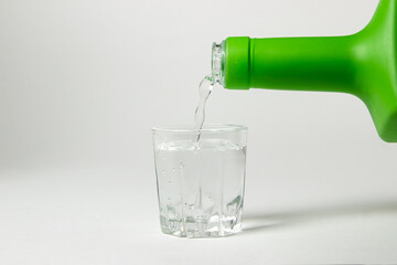 Vodka is poured into a glass on a white background. Strong alcoholic drink. Alcohol addiction