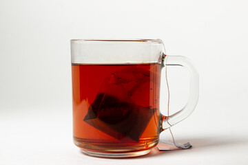 A brewed tea bag in a transparent glass on a white background. A quick way to prepare tea. used tea bag