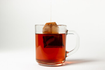 A brewed tea bag in a transparent glass on a white background. A quick way to prepare tea. used tea bag