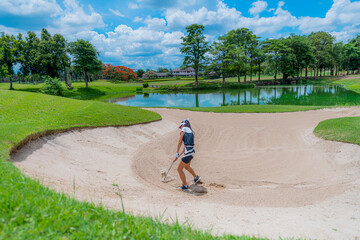 Asian female golfer swings in a sand pit during practice before a golf tournament at the golf course.