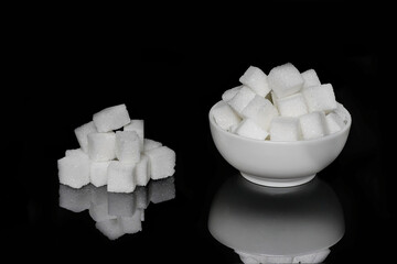 Fototapeta na wymiar Sugar cubes, in a small bowl, next to the pyramid piled up