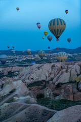 Obraz premium Hot air balloons flying over rock landscape at Cappadocia Turkey with blue sky in the background. 