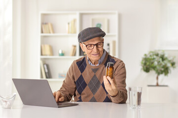 Elderly man sitting at home with a laptop computer and checking pills