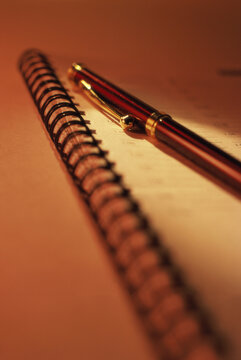 Close-up of a ballpoint pen on a spiral bound notebook