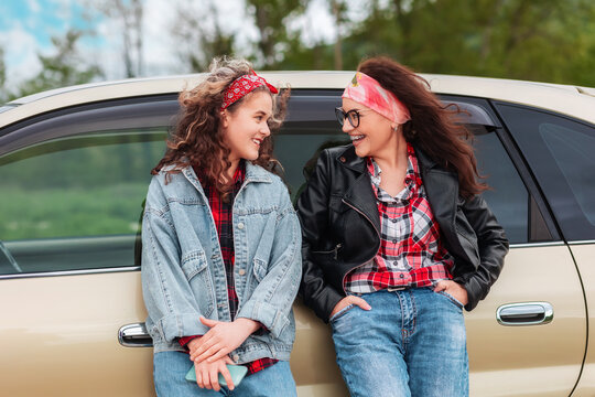 Automobile's Trip. Happy Caucasian Woman And Teen Girl Standing By A Car. The Concept Of Purchase A New Automobile And Driver's License