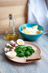 Food. Healthy breakfast. Plate with spinach leaves, green basil, bacon, eggs and a piece of rye bread. Salad of cabbage and eggs. Fragrant spicy olive oil with pepper. Selective focus