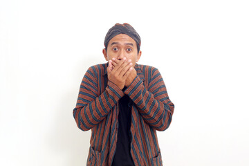 Surprised Asian man standing while covering his mouth. Isolated on white background