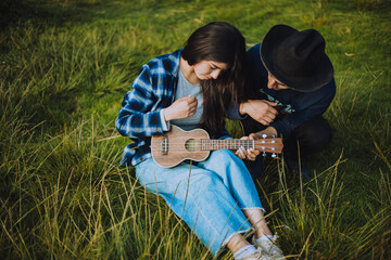 Mujer aprendiendo a tocar Ukulele o guitarra al aire libre. Concepto de educación, música y...