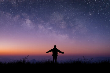 Silhouette of young traveler and backpacker standing and open arm watched the star and milky way...