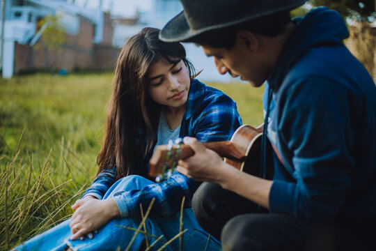 Mujer aprendiendo a tocar Ukulele o guitarra al aire libre. Concepto de educaci&oacute;n, m&uacute;sica y personas.