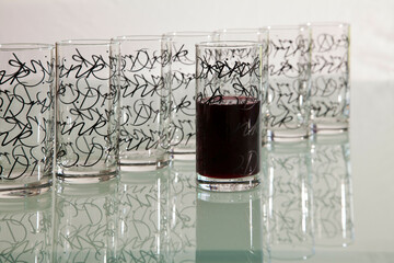 Empty glasses with pattern in row with one filled with drink