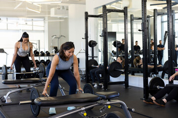 Determined young woman training with free-weights in gym, doing deadlift