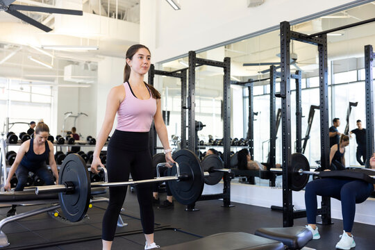Fit, young woman working out with barbells in a fitness gym.