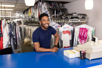 African American man standing behind counter talking to customer at laundromat