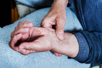 an elderly woman examines her pulse in her wrist