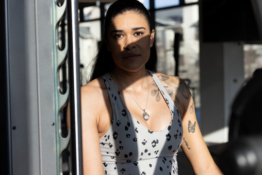 Portrait of woman standing in sunlight in front of exercise machine