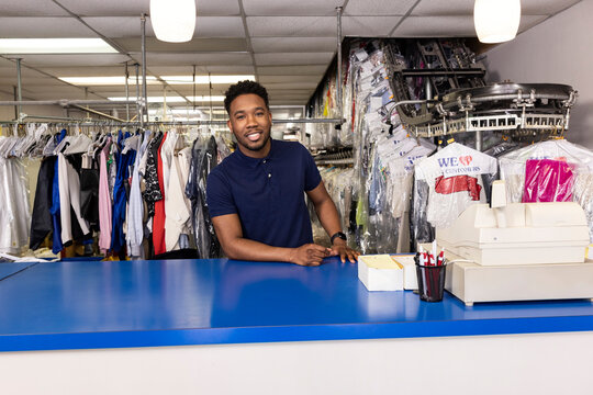 Portrait Of Confident Black Male Business Owner At A Dry Cleaners Facing Camera Behind Counter