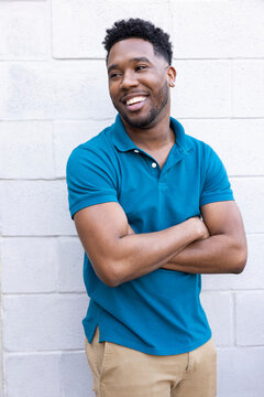 Confident young Black man in blue polo shirt looking off camera smiling.