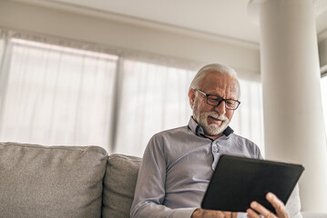 Businessman using digital tablet while sitting on sofa at corporate office