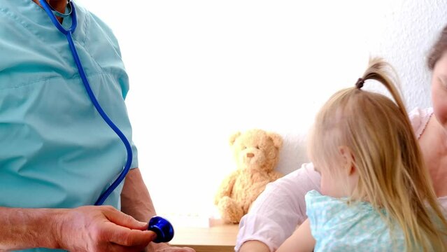 doctor, pediatrician examines, listens to lungs and bronchi of patient with stethoscope of small patient, toddler, small child, blonde girl 3 years old looks trustingly man, concept treating children