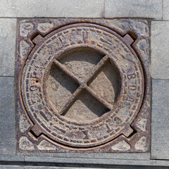 Old shabby manhole cover in the street