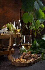 White wine in glasses, pear, cheese plate and grapes.
