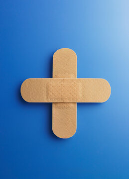 Sticking plasters forming a cross on a blue background