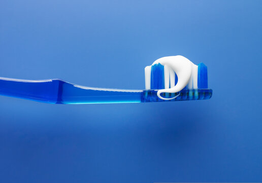 Close up of toothbrush and toothpaste with blue background
