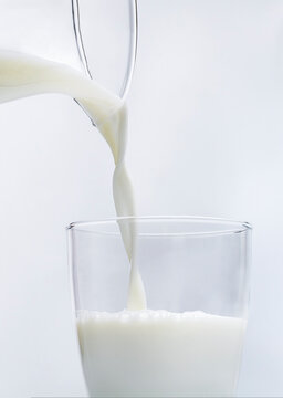 Milk being poured from glass jug to tall glass