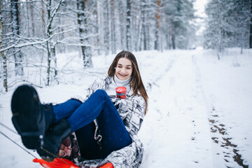 Fototapeta na wymiar girl in a winter snowy forest sledding. winter fun in the woods 