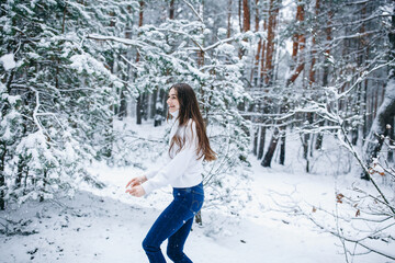 beautiful woman with long hair in a white sweater with a snowy winter forest
