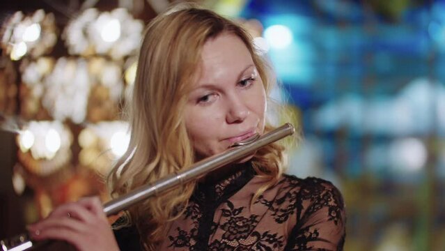 Blonde woman playing flute and looks in the camera