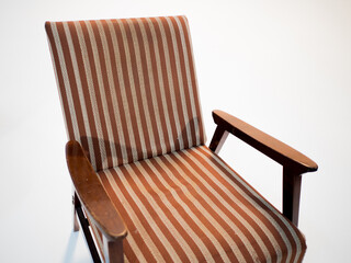 Stylish retro striped armchair with armrests on a white cyclorama