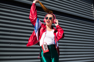 Back in time 90s 80s. Stylish girl in retro jacket and vintage cassette player listens to music,...