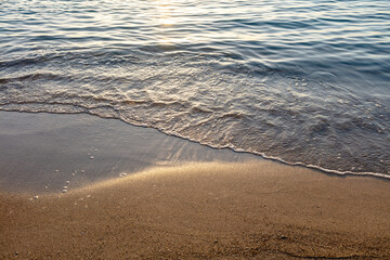 Empty sandy beach at sunset, Greece, overhead. Sea water touch wet sand, copy space. Summer holiday