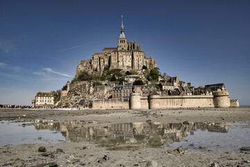 Panoramic view of famous historic Le Mont Saint-Michel tidal island on a sunny day with blue sky
