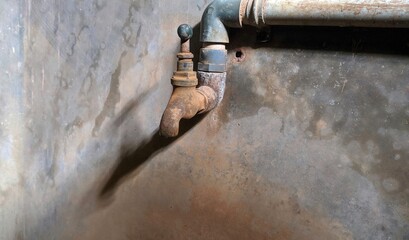 Closed dirty vintage damaged old rusty metallic bronze drinking water faucet tap or pipe on a...