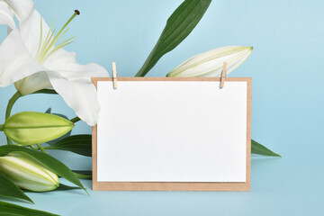 The template is a blank sheet of paper and an envelope with space for text on a light blue background with lily flowers.