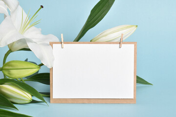 The template is a blank sheet of paper and an envelope with space for text on a light blue background with lily flowers. © Irina Lesovaia