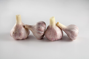 There are four heads of garlic on the table. On a white background.
