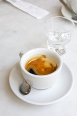 A cup of espresso and a glass of water after coffee.