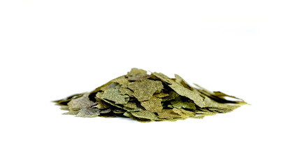 Dry handful, bunch green compound fish feed flakes on White background. Side view