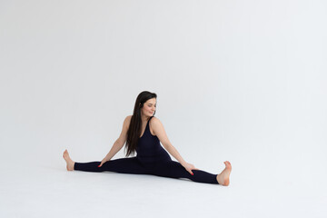 Young beautiful woman practicing yoga on a white background. Young beautiful girl doing exercises at home. Harmony, balance, meditation, relaxation, healthy lifestyle concept 